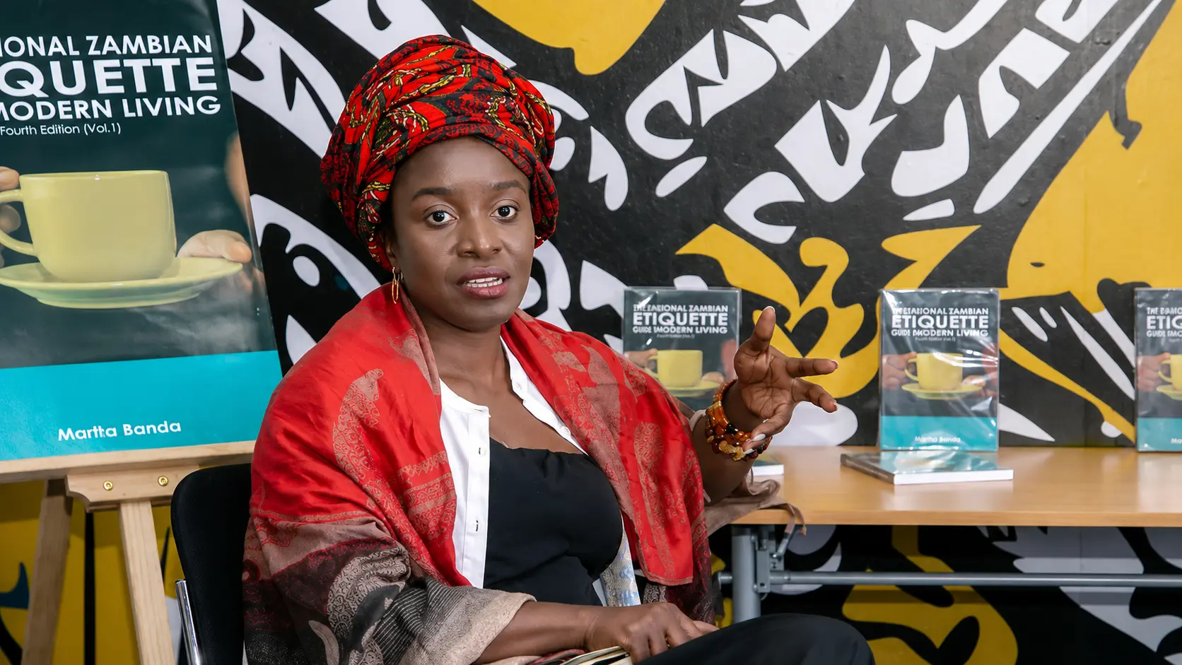Marita Banda speaking beside copies of her book